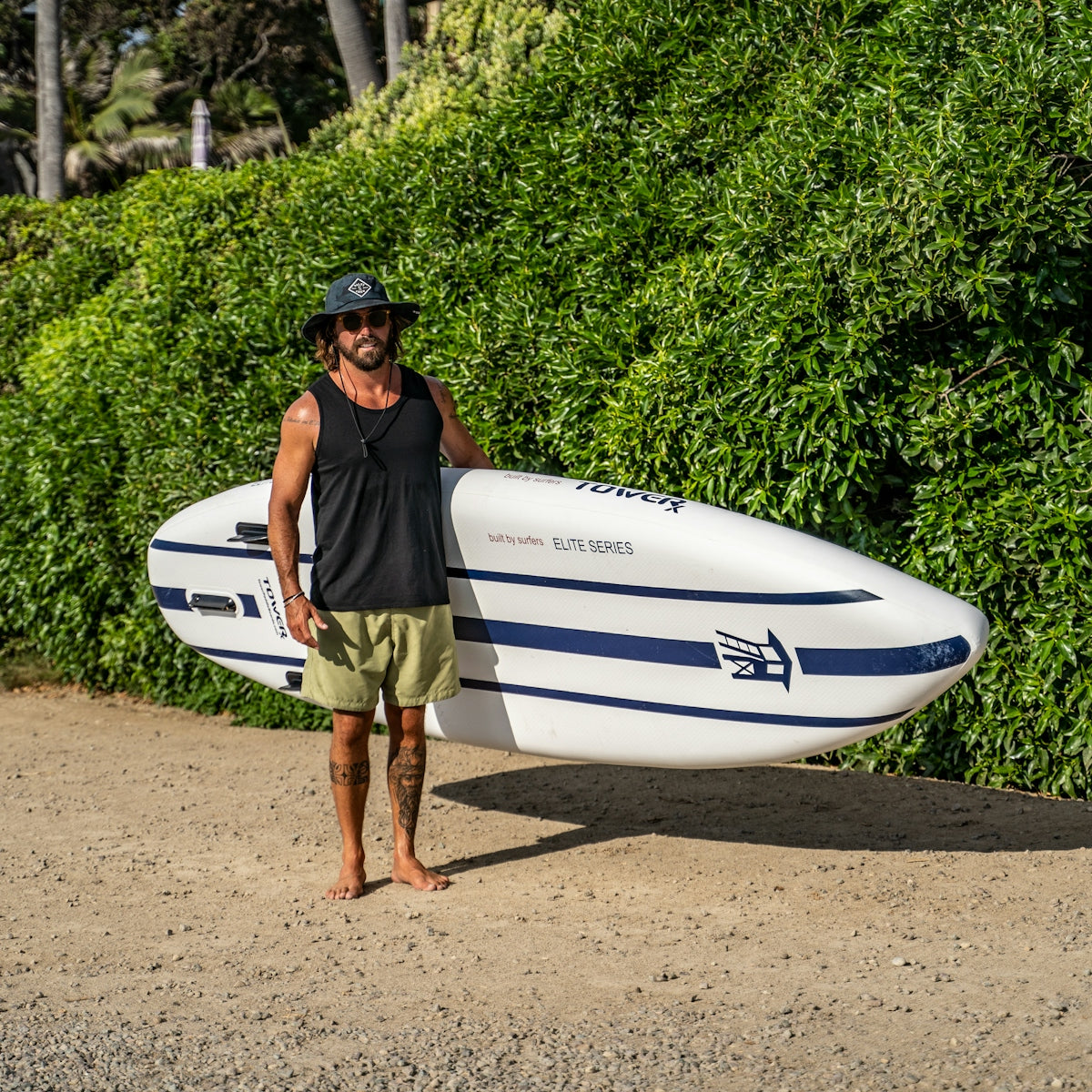 a man holding a surfboard on a dirt road